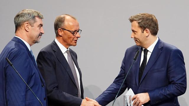 Friedrich Merz und Lars Klingbeil geben sich nach der Vorstellung des Koalitionsvertrages die Hand, links steht Markus Söder