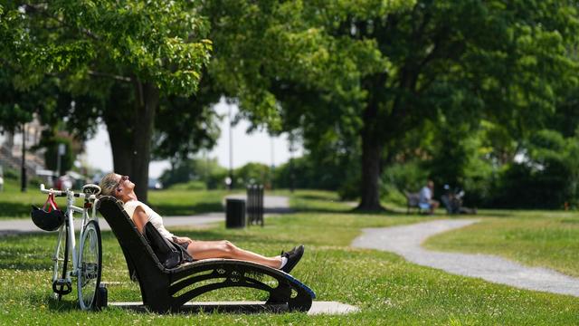 Une Montréalaise prend un bain de soleil dans un parc.