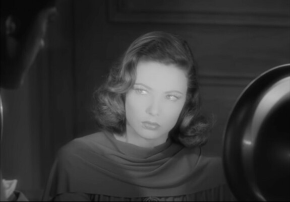 Gene Tierney (Laura) is caught in a spotlight while being interrogated by a shadowy Dana Andrews (Detective Mark McPherson)