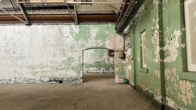 Interior of former Magdalen laundry, with pipe works exposed and green paint peeling from the walls of the crumbling large space