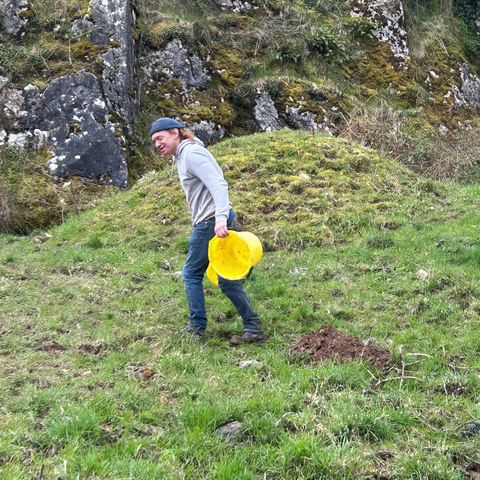Phil Kenny, with two empty yellow buckets and just emptied cave sediment onto small spoil heap - our first of this excavation!