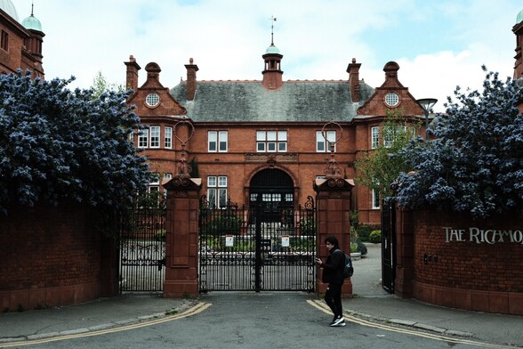 A red brick building with lots of blue flowers 