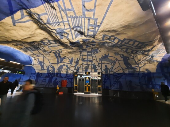 Art: Blue painting of building worker along the cave like wall and roof in an underground train station in Stockholm, Sweden. 