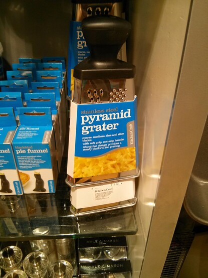 A kitchen utensil on a store shelf, branded "Pyramid Grater"