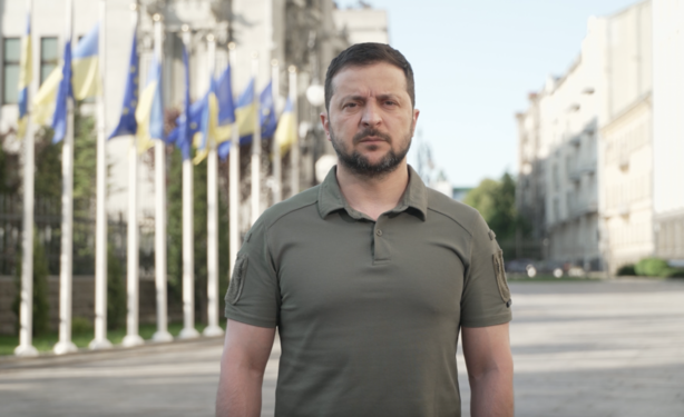 Zelensky standing in a street with Ukraine flags in the backgroung