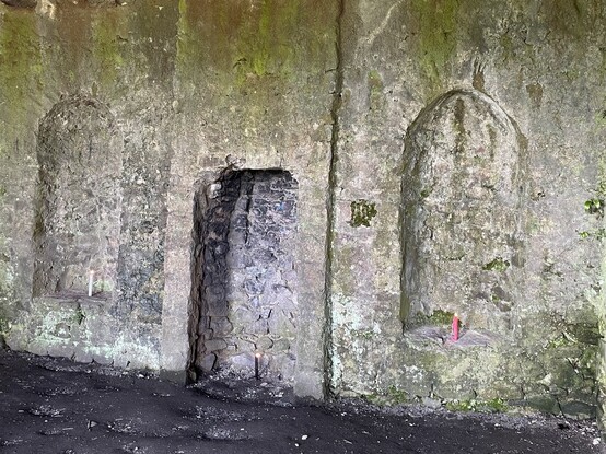 Three lit candles in alcoves and fireplace in the ruined interior of the Hell Fire Club