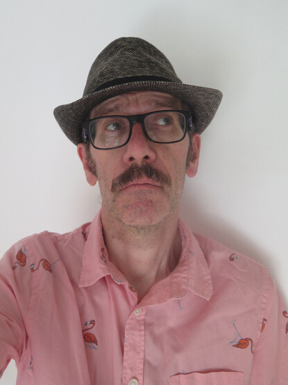 It's the same guy in the same clothes (brimmed hat, glasses, moustache (part of his face, not clothes), and short sleeved shirt (salmon coloured, with flamingos). This time his face is full on to camera but his eyes look off to one side.