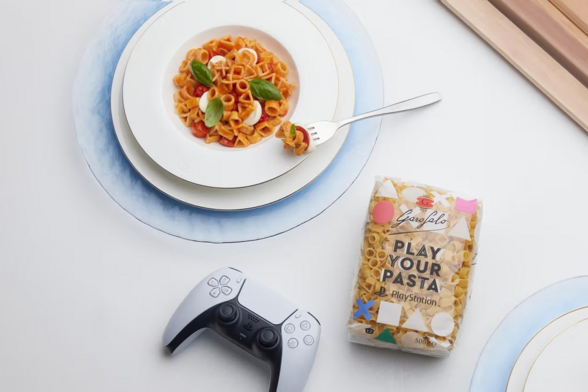 A plate of pasta in the shape of the PlayStation face button (Triangle, Cross, Square and Circle) 

There is also a sealed bag of the Pasta with the words "Play Your Pasta"

and a PlayStation 5 controller. 