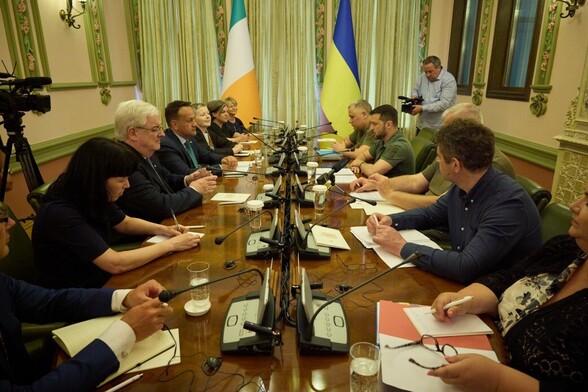 Delegates from Ireland and Ukraine sitting at a conference table facing each other with  Irish and Ukraine  flags in the background