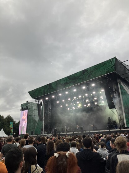 MUNA on stage at the Royal Hospital Kilmainham, Dublin, with dramatic lighting. 