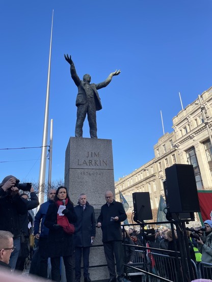Ní Shéaghdha and others stand beneath the statue of labour leader, Jim Larkin, and the caption: "The great only appear great because we are on our knees. Let us rise!"