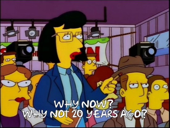 Scene from the Simpsons, featuring a crowd of characters with cameras and microphones, with text reading "WHY NOW? WHY NOT 20 YEARS AGO?"