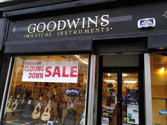 Goodwins music shop front with large banner indicating "retirement, closing down. Sale"