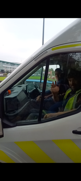 Two Bus Éireann employees waving sarcastically at me from their van.