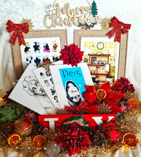 Photograph of a display of prints, surrounded by Christmas decorations and fairy lights, against a white fluffy background 