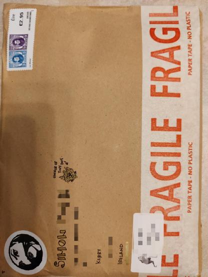 A brown rigid envelope with personal details blocked off.

There is a drawing of a woman on the top right of the artist with her hair across her face as a silly mustache (that would be the exceptional @ciaraioch 

She has also drawn a miniature version of my dog to indicate I am the owner of said pup to make me easier to find 🐾