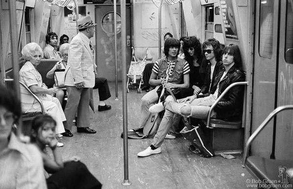 Interior of subway car with young band on one side and older folks on the other, with other random passengers in fore and background.
