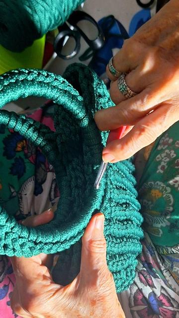 Elderly hands wearing fab handcrafted silver rings, crocheting a bag