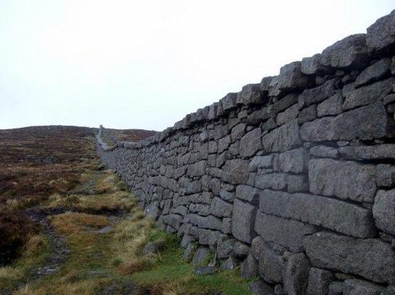 Looking along the Mourne Mountain wall at Hare’s Gap. The wall here looks like the stones have been shaped to make a much more closely knit structure. The top row of stones jut out over the wall.