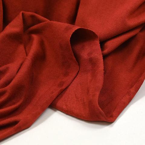 A store photo of terracotta red Jersey showing the fabric slightly bunched up on a white background 