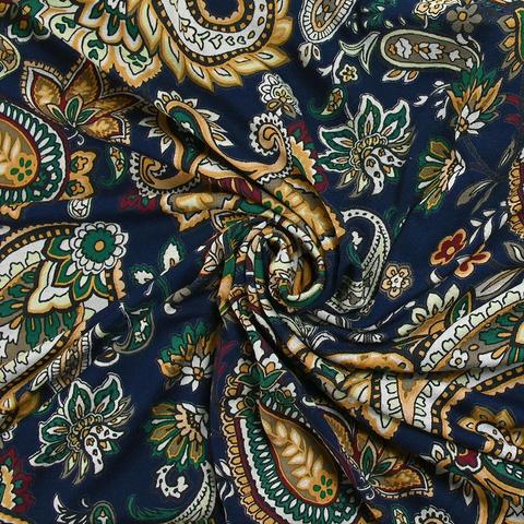 Navy jersey fabric with a busy paisley print on top in mustard yellow with white, blue, and dark green accents. It's laid out flat, but with a twist in the middle. 