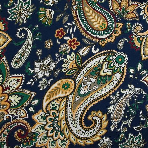 Navy jersey fabric with a busy paisley print on top in mustard yellow with white, blue, and dark green accents. It's laid out flat to show the pattern clearly.