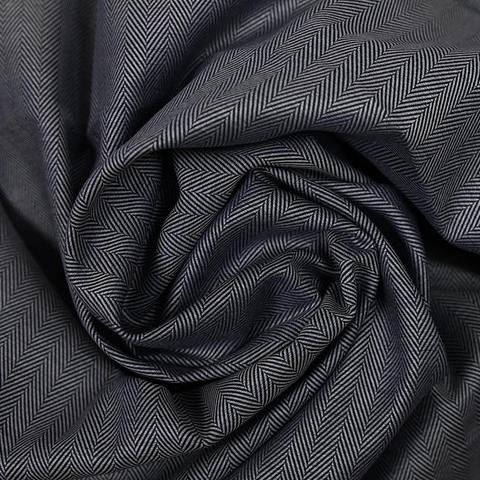 Satin cotton fabric with a delicate chevron pattern in white and navy, swirled and photographed from the top. The fabric texture causes deep shadows and bright highlights 