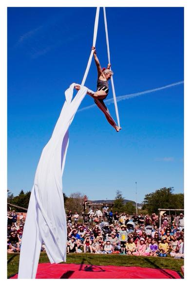 Suspended Tumble Circus performer and flowing fabric high above the playground doing the splits mid air with thousands of kids watching on. 