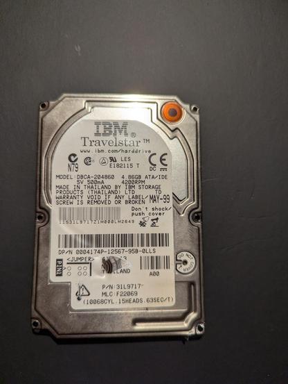 Photo of a production label of a harddrive on a bent backplate photographed on a black background. It's a 4GB ATA/IDE drive with production date of MAY-99