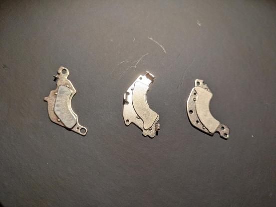 Same magnets as before but photographed from underneath showing the magnet proper, a smaller curved piece, on the metal larger pieces.