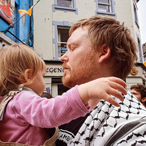 Denman wearing a Palestinian kufiya while holding his daughter