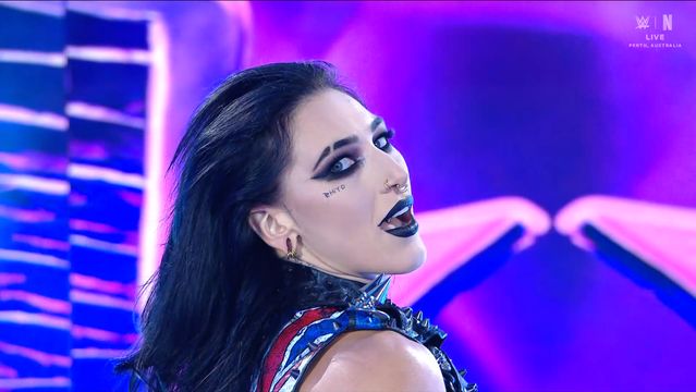 Rhea Ripley at WWE Crown Jewel 2025 in Perth, Australia.
She has "RHIYO" under her right-eye which is a mash of her name and her tag team parner IYO SKY

Top right is the WWE and Netflix logo
LIVE
PERTH, AUSTRALIA!