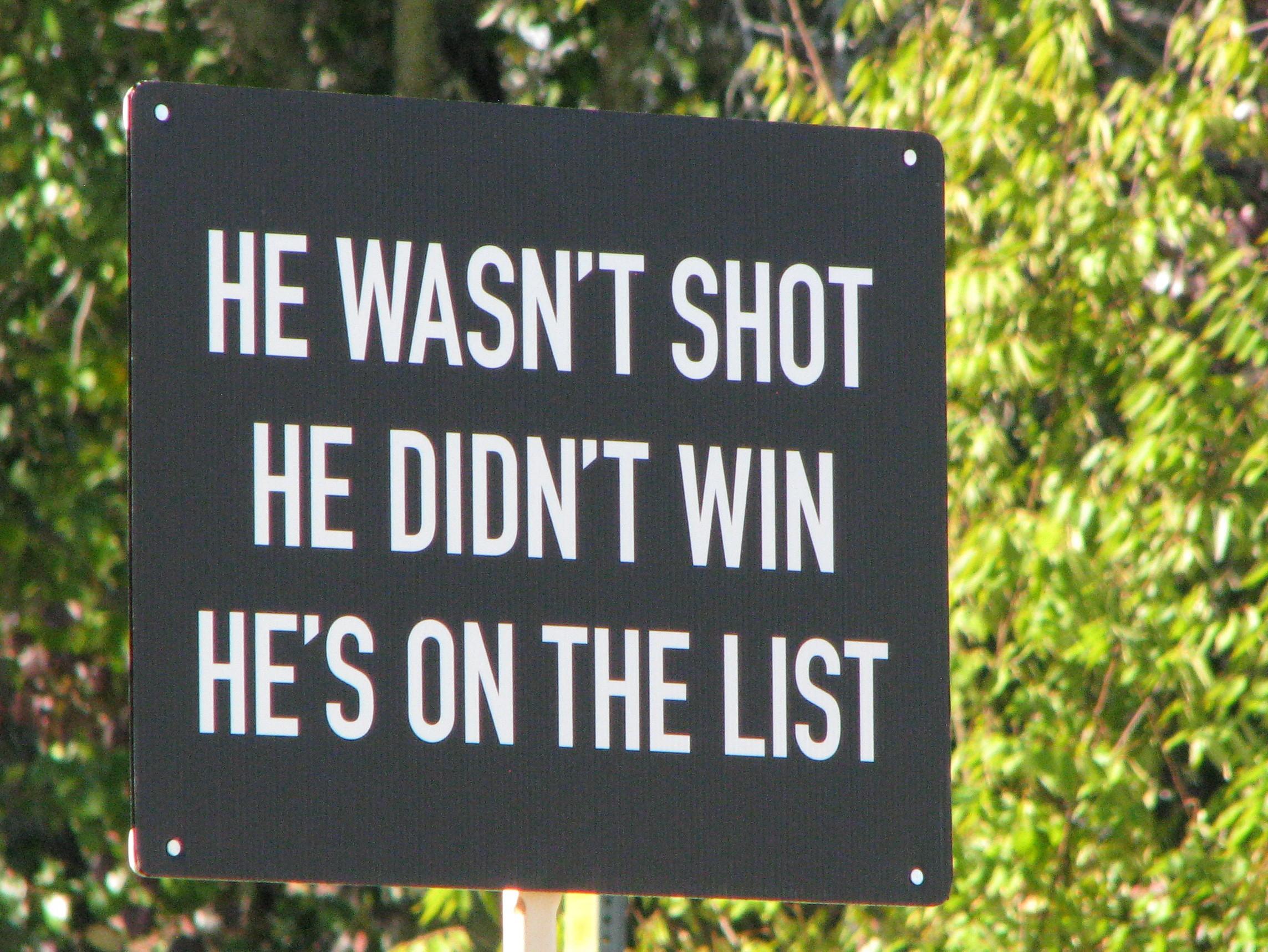 Protest poster. White text on black, which reads "He wasn't shot. He didn't win. He's on the list."