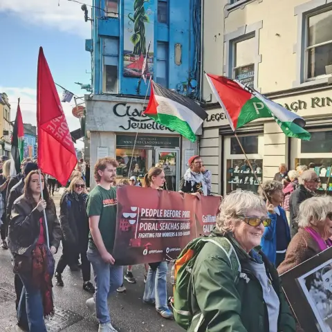 PBP activists marching in Galway City with a banner and Palestine flags