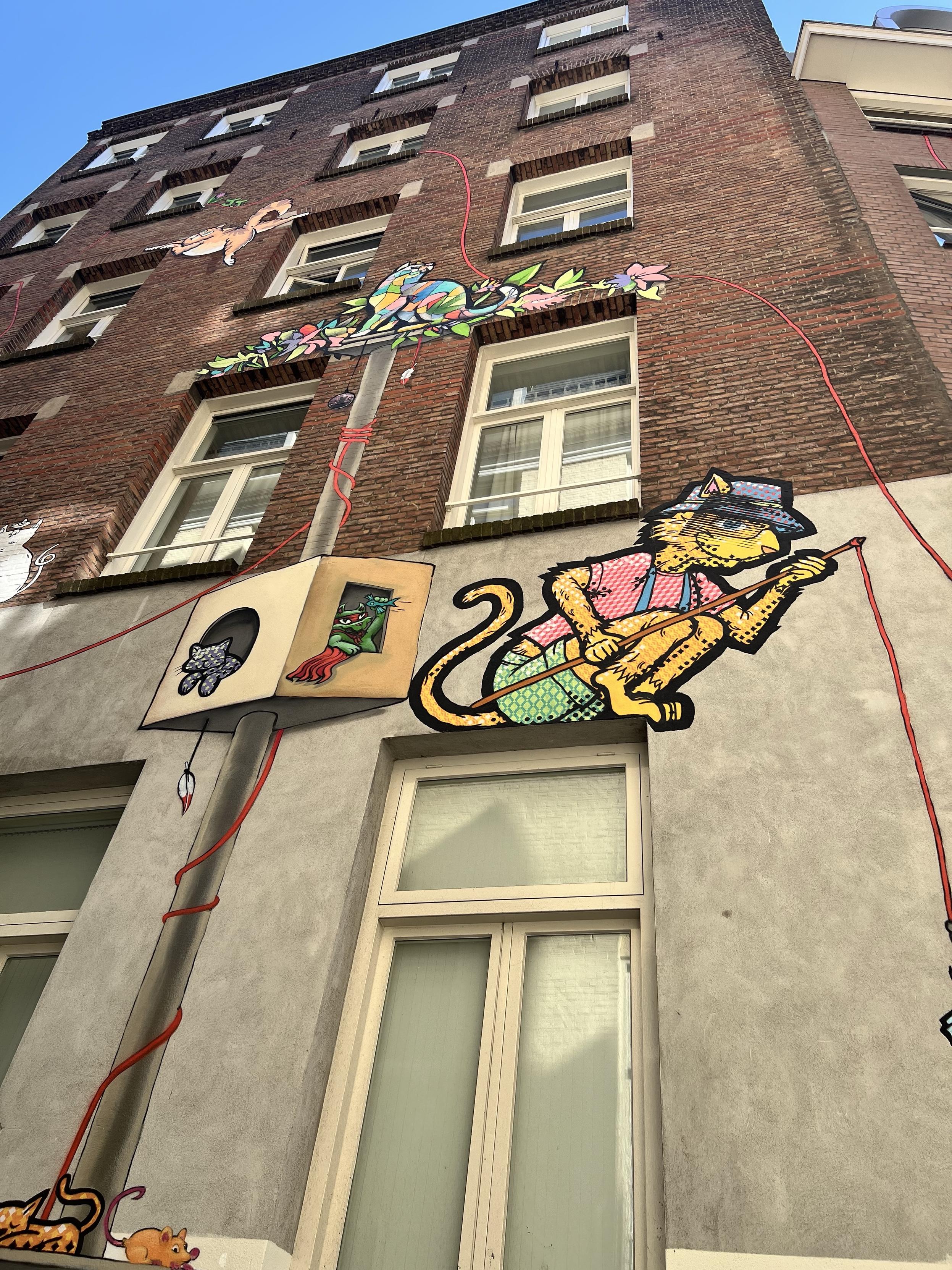 A photo of the side of a building covered in different street art cats. All different stiles. Going up several floors.