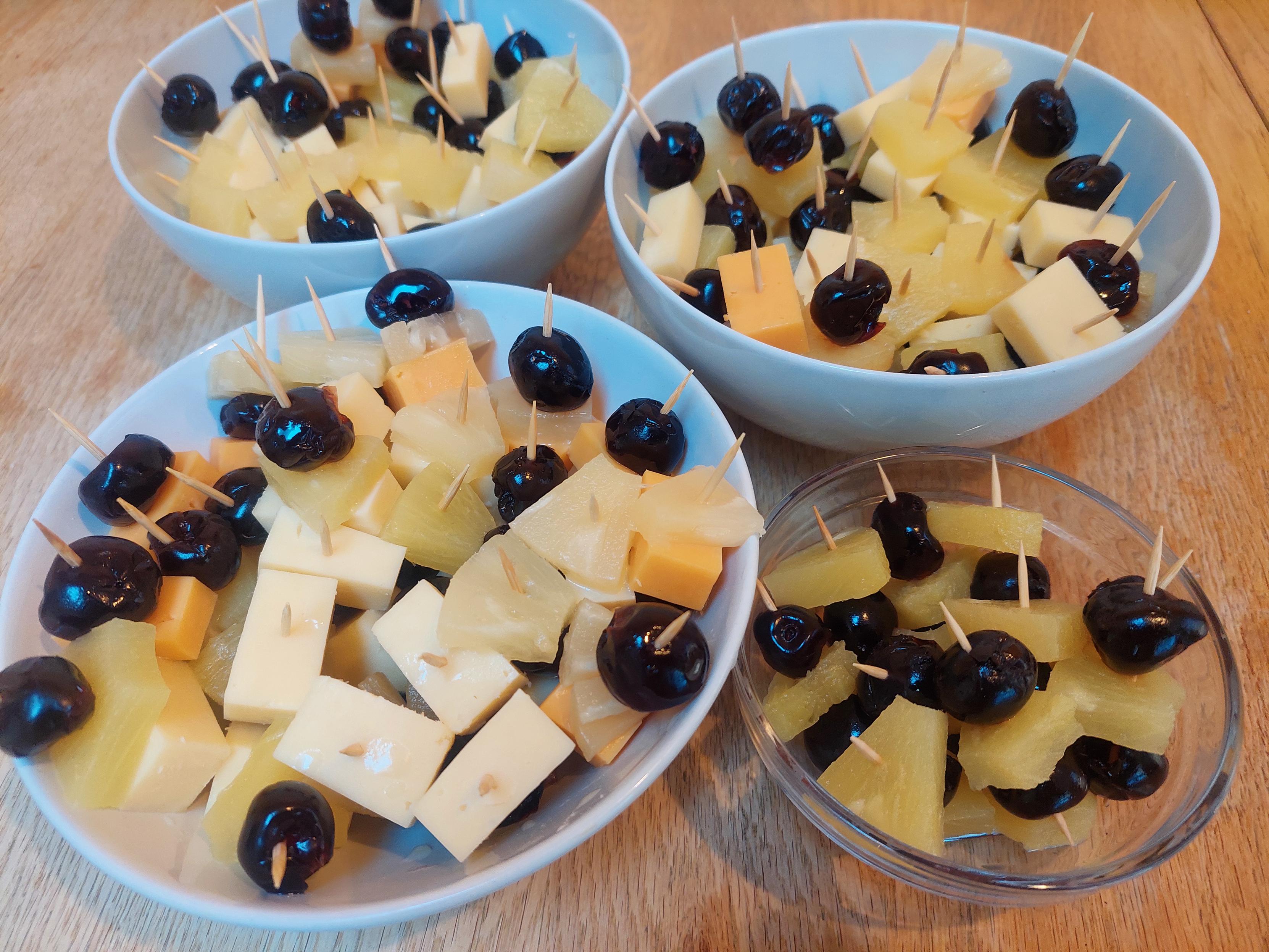 4 bowls with cheese, pineapple, and cherries on cocktail sticks.