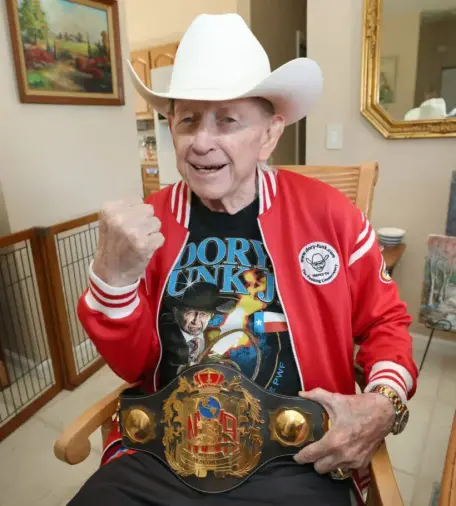 Dory Funk Jr. poses with a replica of his Heavyweight Wrestling Champion of the World belt at his home in Ocala, Fla. on Jan. 23, 2026. He passed away Aug. 4 in Ocala. [Bruce Ackerman/Ocala Gazette file photo]

Source: https://www.ocalagazette.com/a-great-one-is-gone/