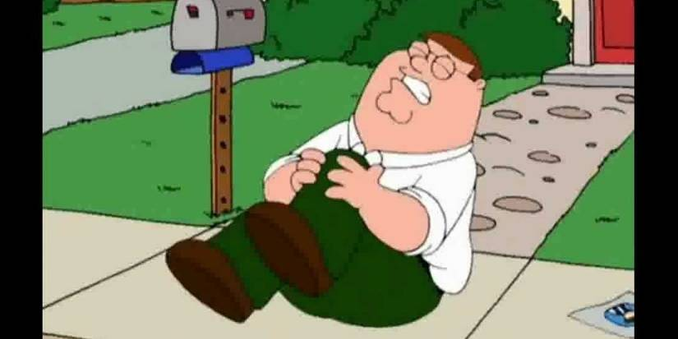 Peter Griffin from Family Guy sitting on the footpath clutching his left knee in agony. 