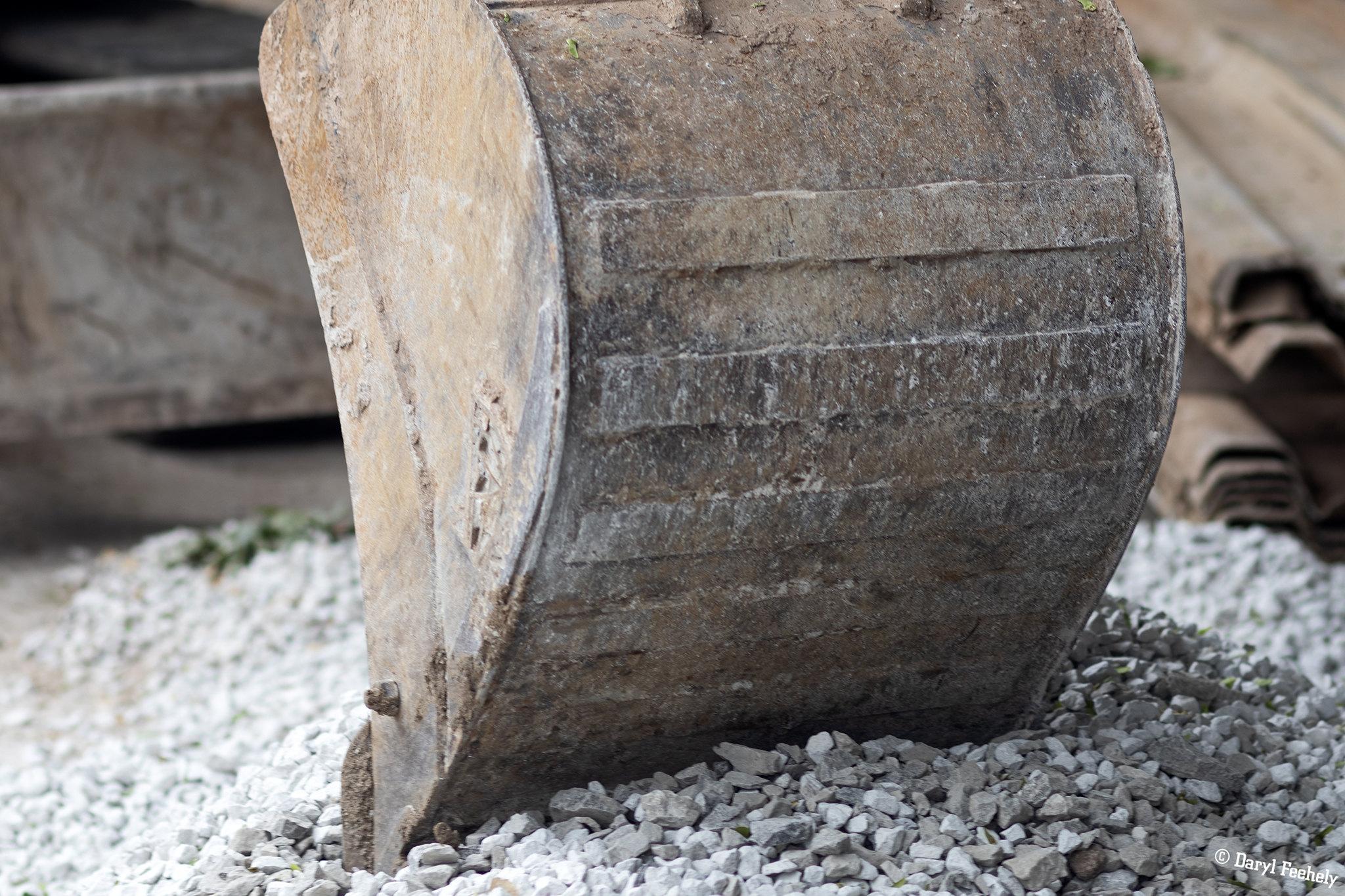 The bucket of a digger resting on gravel.