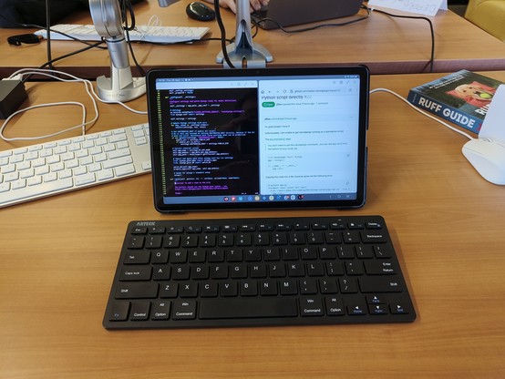 A tablet on a stand, showing code, with a Bluetooth keyboard in front.