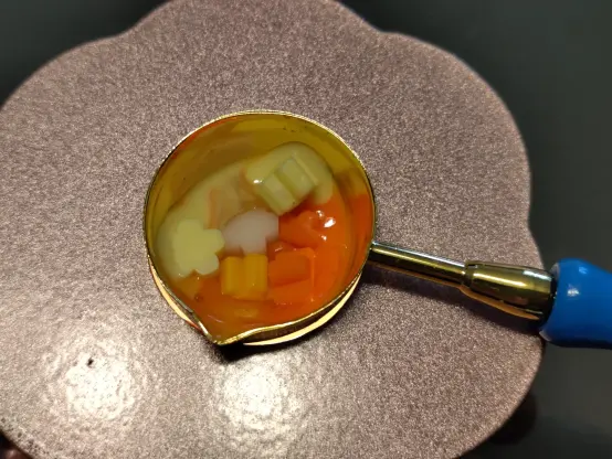 A tiny spoon with sealing wax in it melting.