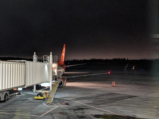 An Air North Boeing 737 seen in the dark from the departure ramp. The sky is dark in the background. 