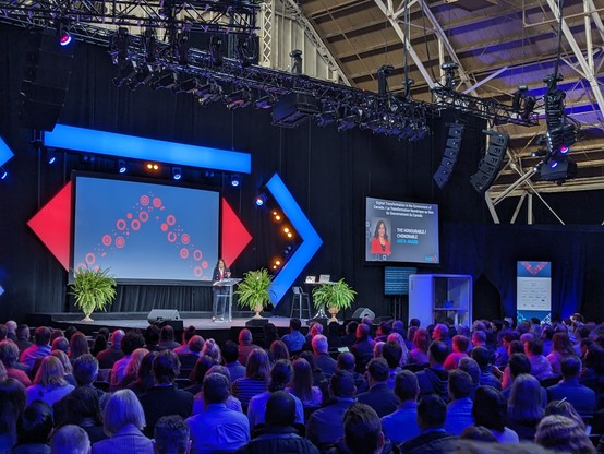 Minister Anand on stage with a crowd of FWD50 attendees in the foreground. 