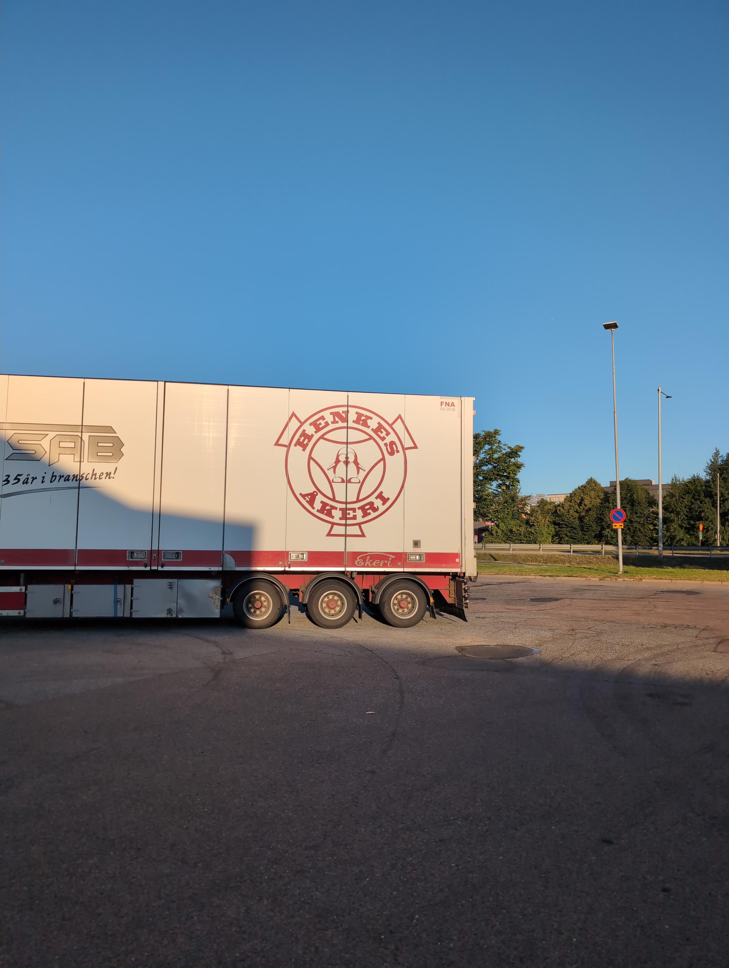 Bakdelen av en lastbilstrailer med loggan på åkeriet, en kombination av Scania Vabis logga utan grpen och med  "crazy tux" istället.
