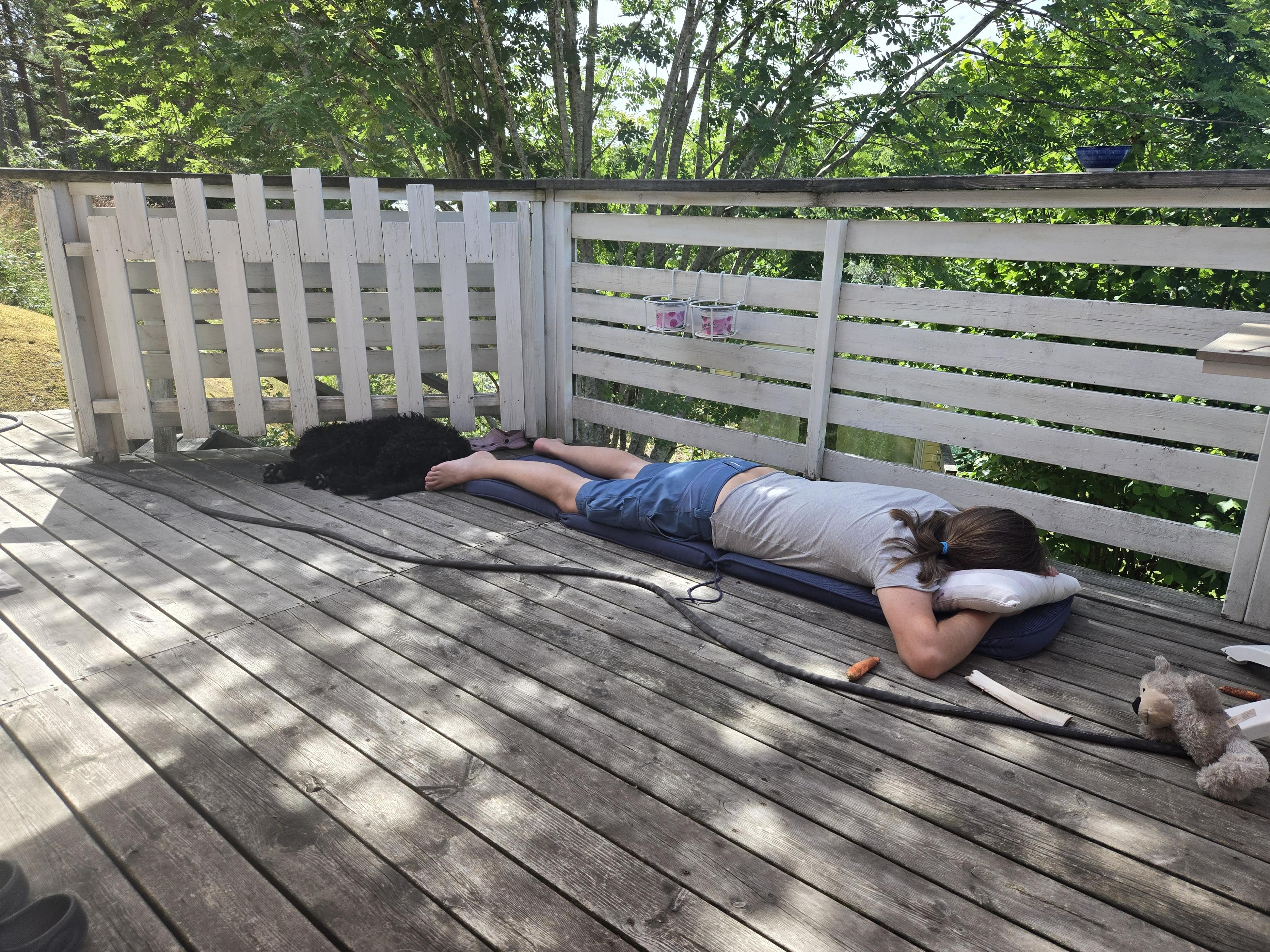 Black doggo baby and grown up male human lying on the porch napping together