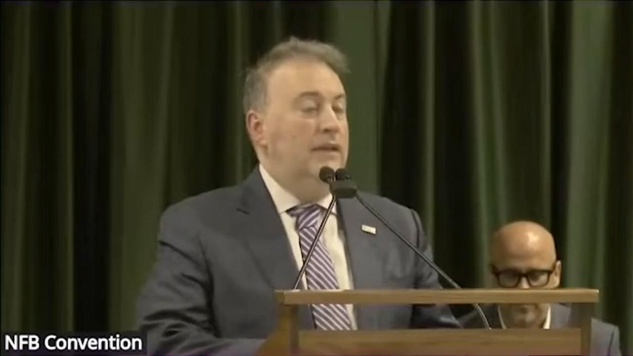 Mike Calvo speaks from a podium at the 2026 National Federation of the Blind Convention.