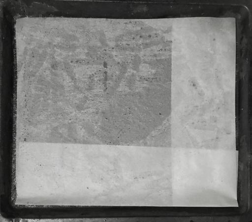 Käytetty leivinpaperi pellillä. Paperin oikea reuna ja alareuna taitettu alle, jotta pelliä suurenpi arkki sopii pellille.