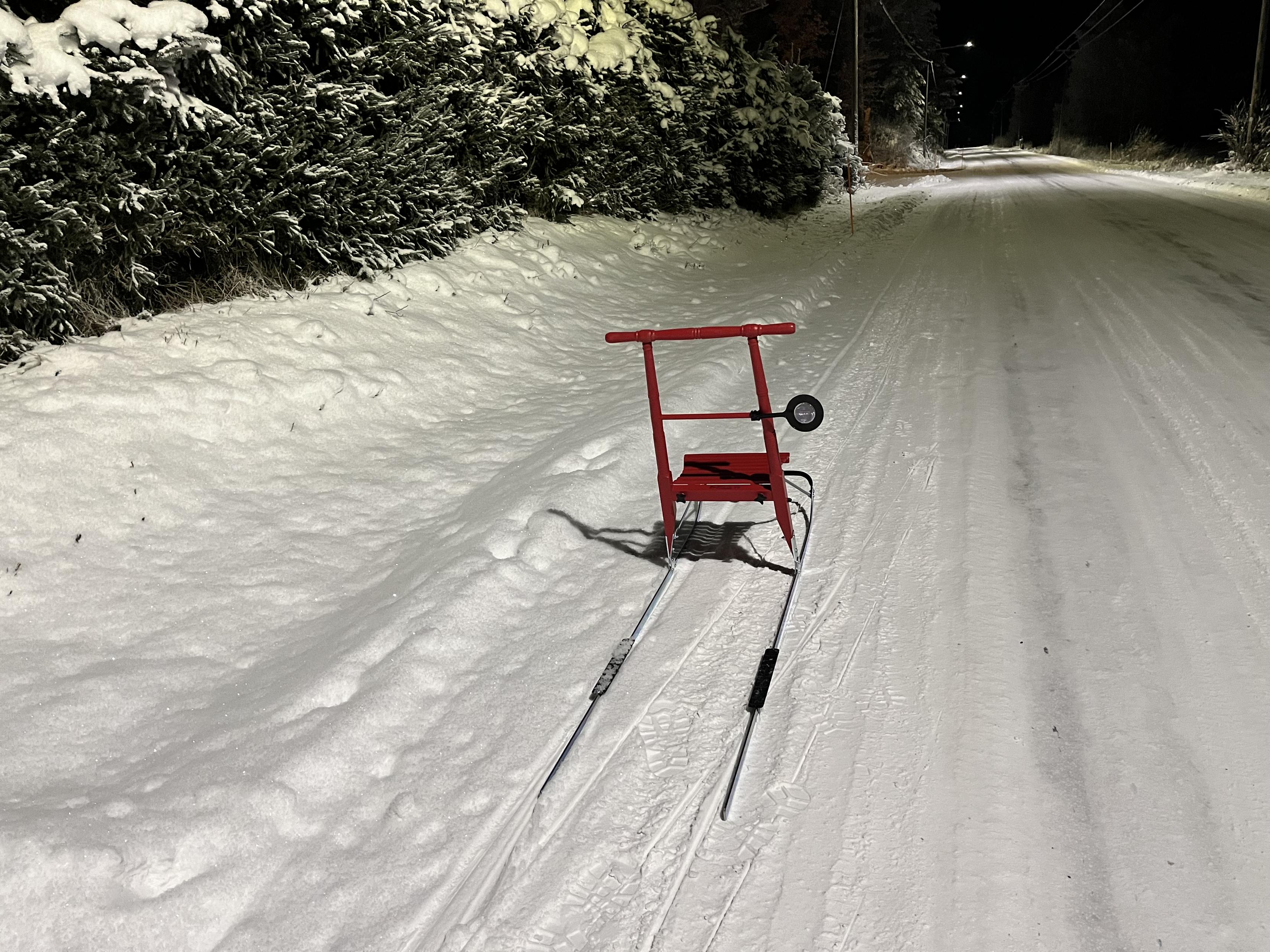 Punainen potkukelkka lumisella tiellä