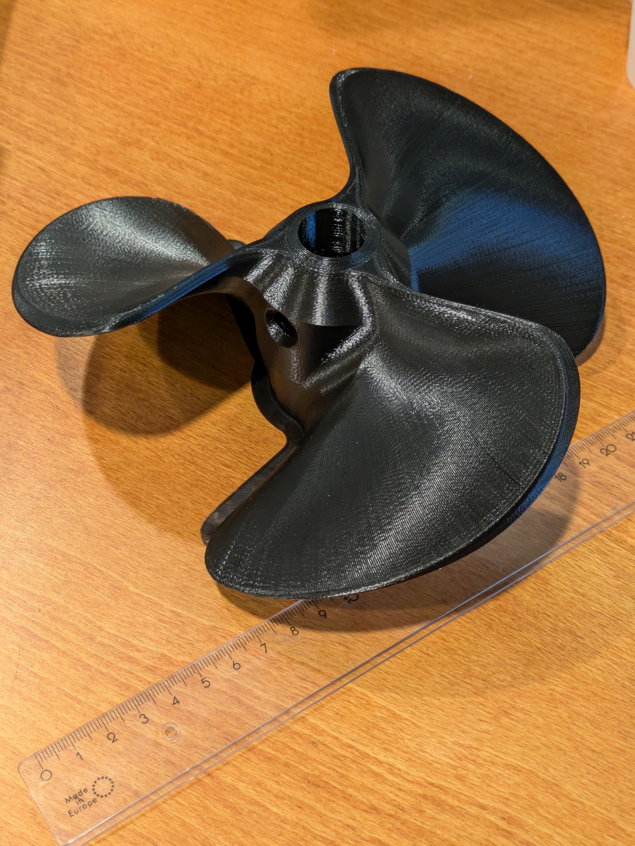Musta 3d tulostettu potkuri. Kuvassa myös viivotin joka paljastaa potkurin olevan noin 20cm halkaisijaltaan.