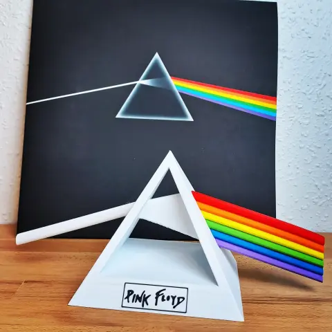 Au premier plan, la "statue" que j'ai modèlisé et imprimé, composé d'une pyramide blanche évidée avec un rai de lumière le traversant, représenté par une tige blanche à gauche et 6 tiges aux couleurs de l'arc-en-ciel à droite.
Au second, le vinyle de Pink Floyd "Dark Side of the Moon"